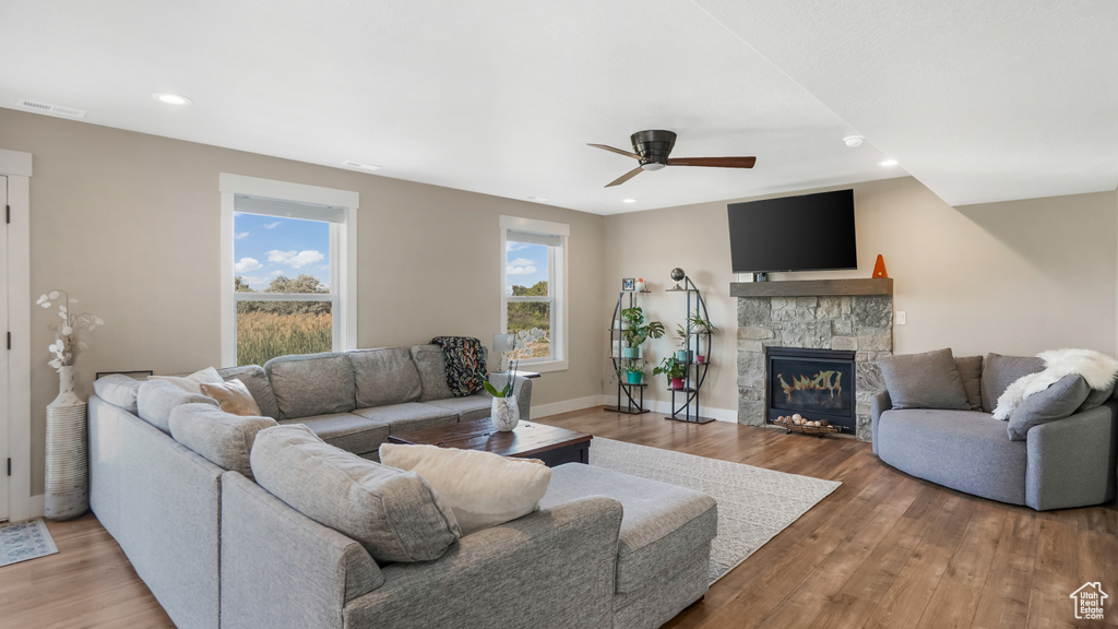 Living area featuring a ceiling fan, light wood finished floors, a stone fireplace, baseboards, and recessed lighting