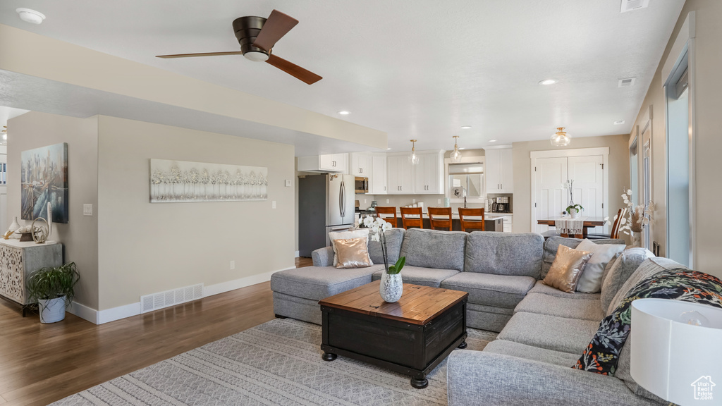 Living area featuring wood finished floors, a ceiling fan, baseboards, and recessed lighting