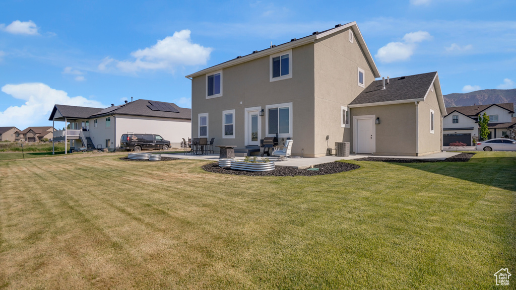 Back of property with a patio area, stucco siding, a yard, and a residential view