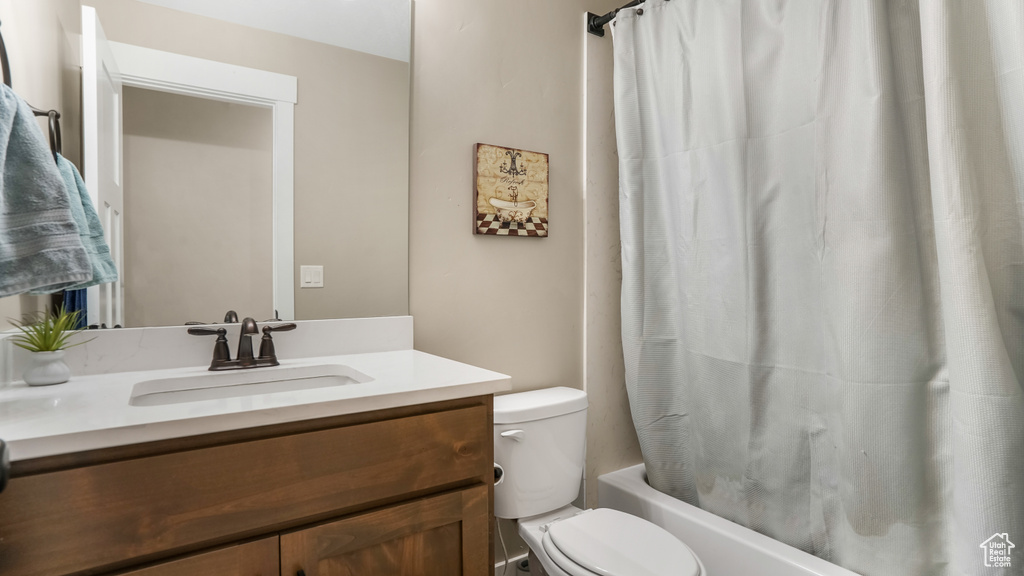 Full bathroom with toilet, vanity, and shower / tub combo with curtain