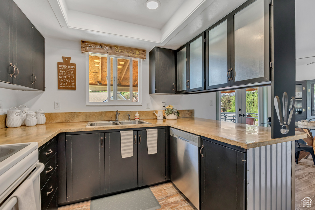 Kitchen with stainless steel dishwasher, a sink, a peninsula, french doors, and a tray ceiling