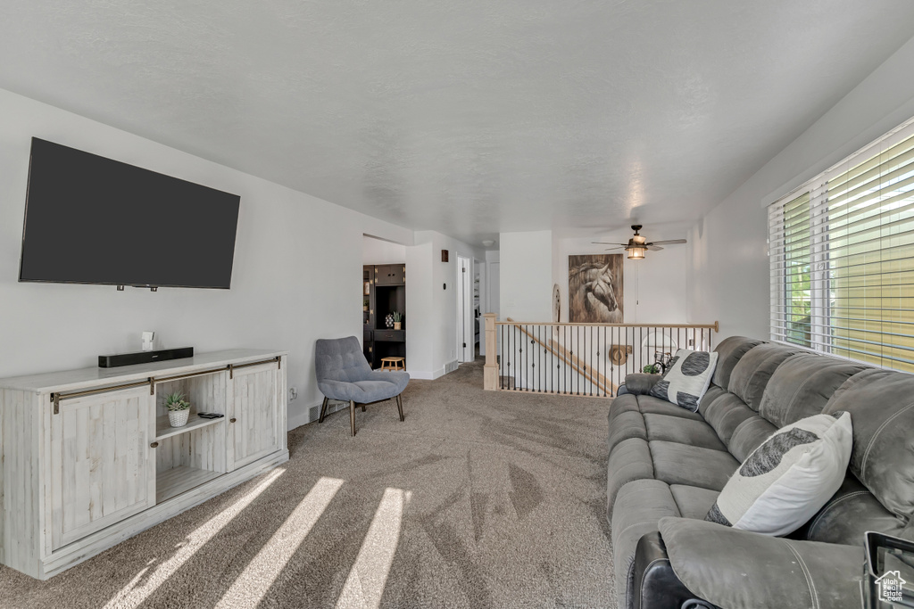 Living room with light carpet, ceiling fan, and baseboards