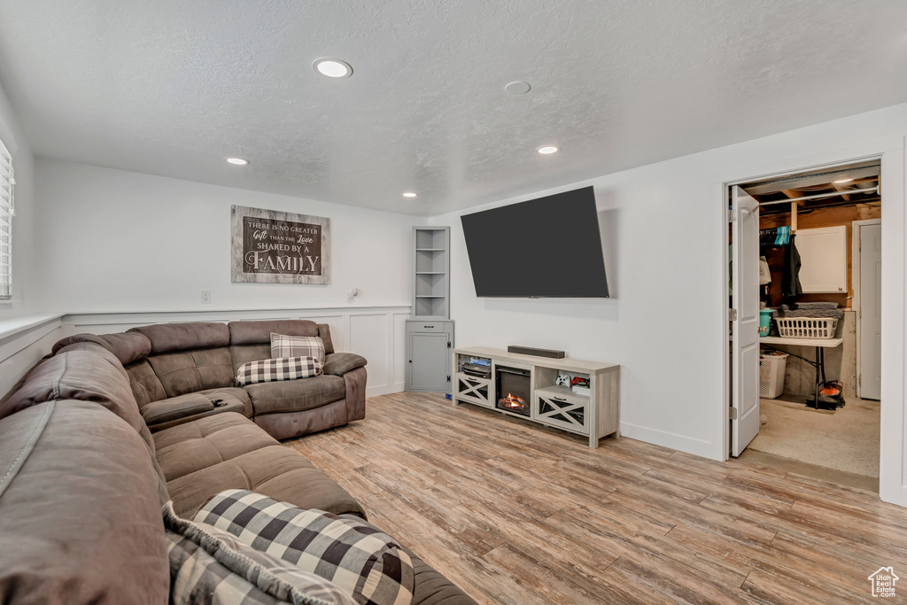 Living area with recessed lighting, wood finished floors, and a textured ceiling