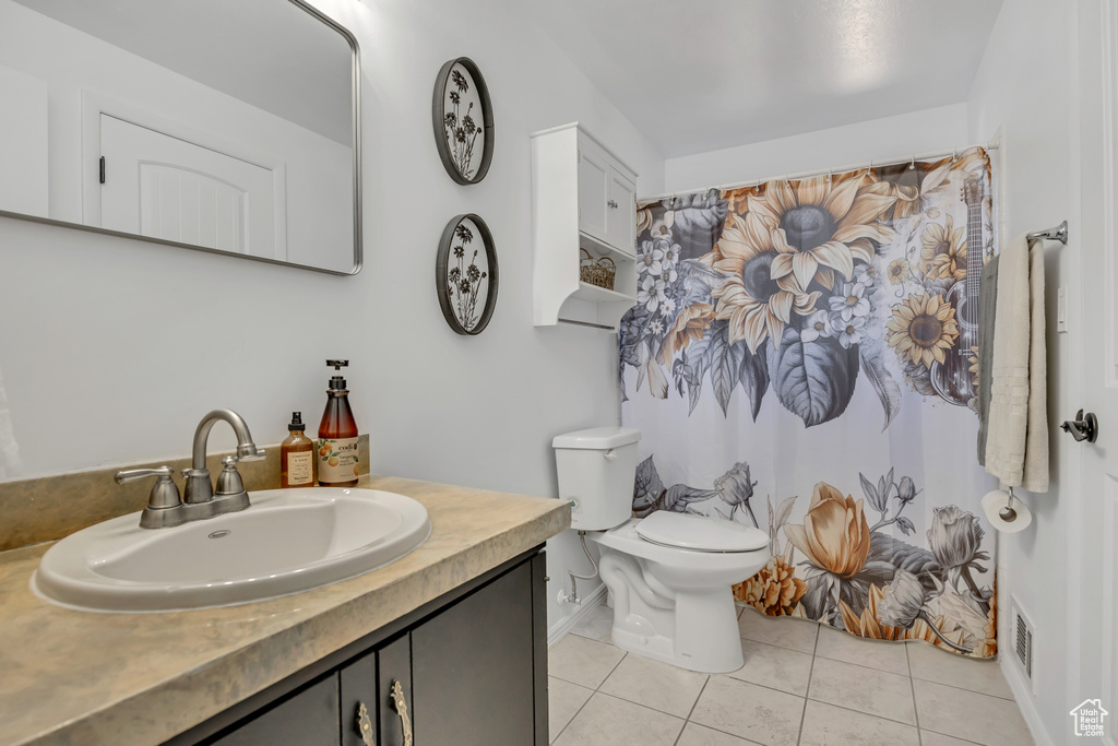 Full bath featuring tile patterned flooring, vanity, toilet, baseboards, and curtained shower