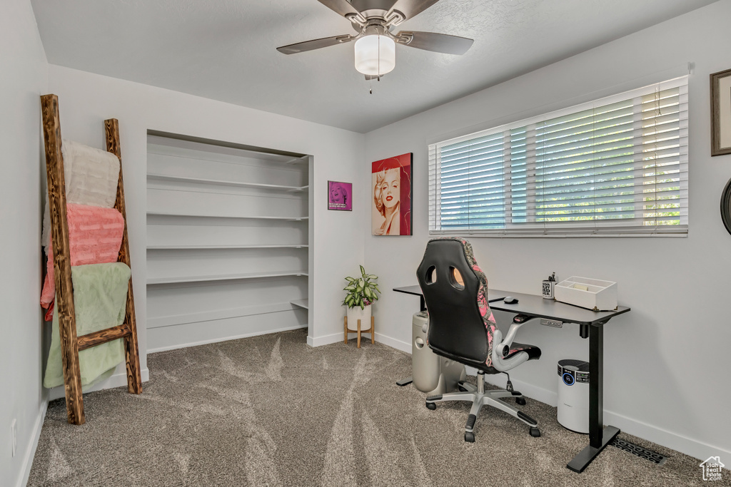 Carpeted office space with ceiling fan and baseboards
