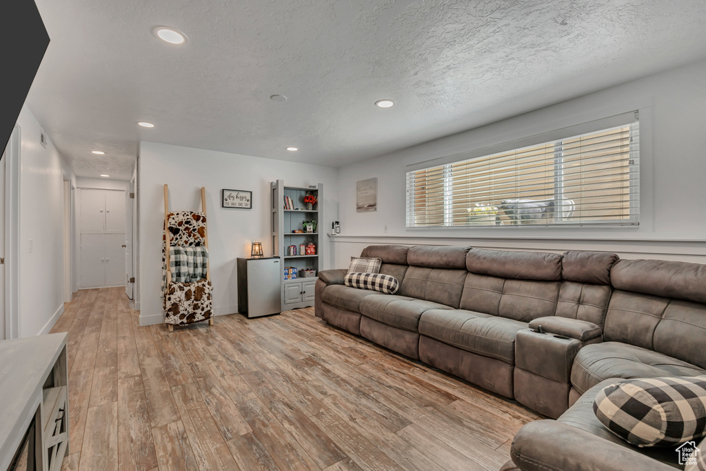 Living room with light wood-style floors, recessed lighting, and a textured ceiling