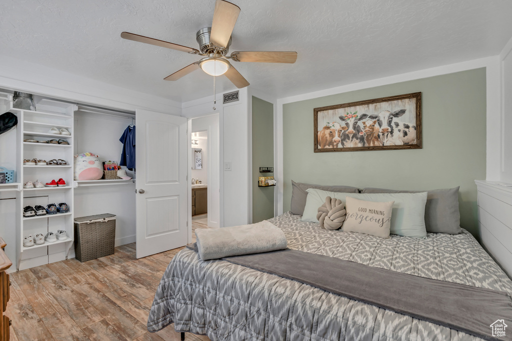 Bedroom with wood finished floors, ceiling fan, and a closet