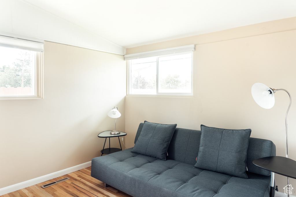 Living area featuring vaulted ceiling, healthy amount of natural light, wood finished floors, and baseboards