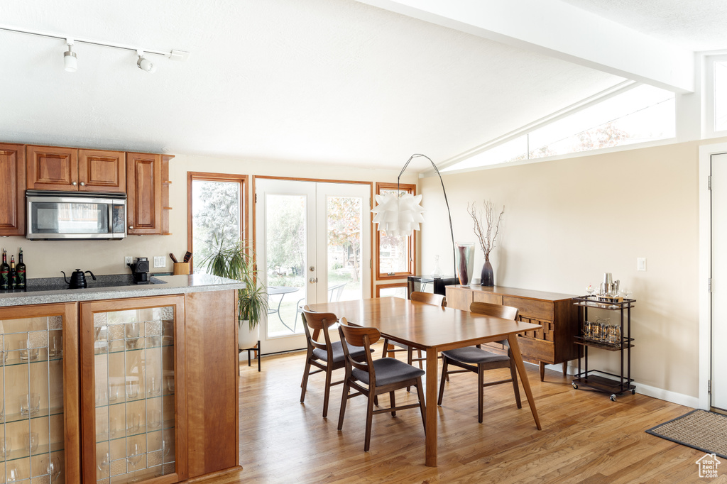 Dining area with light wood-style floors, rail lighting, french doors, and baseboards