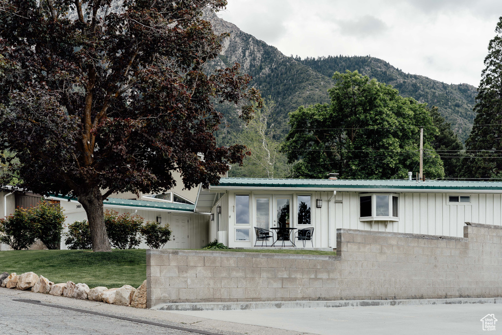 View of front of property with board and batten siding, a mountain view, metal roof, and a front lawn