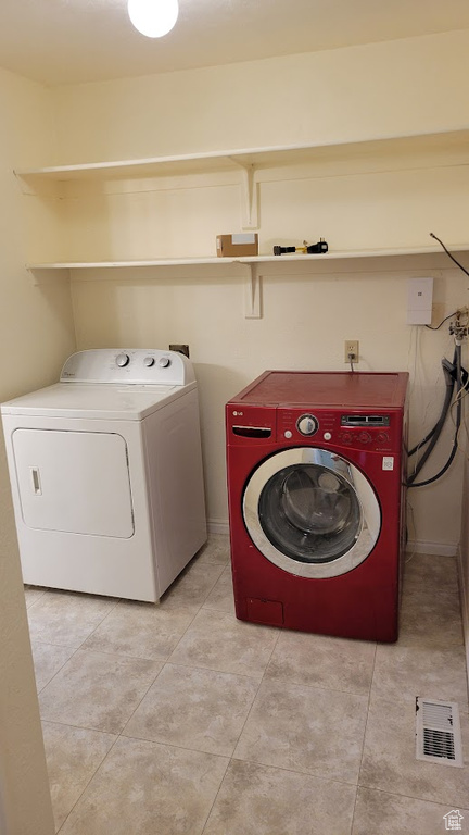 Laundry area featuring washing machine and clothes dryer and light tile patterned floors