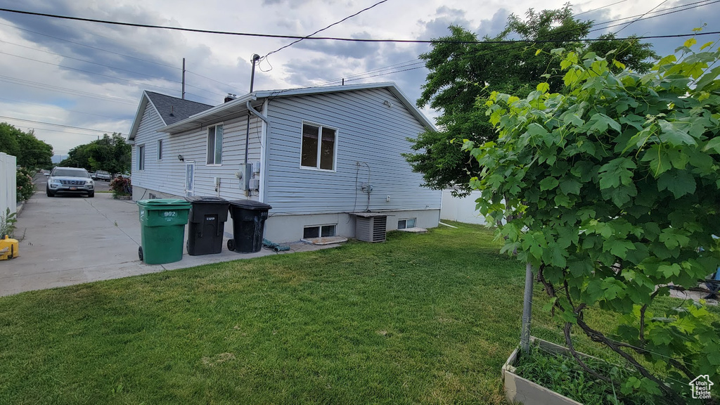 Back of property with a lawn and central AC unit