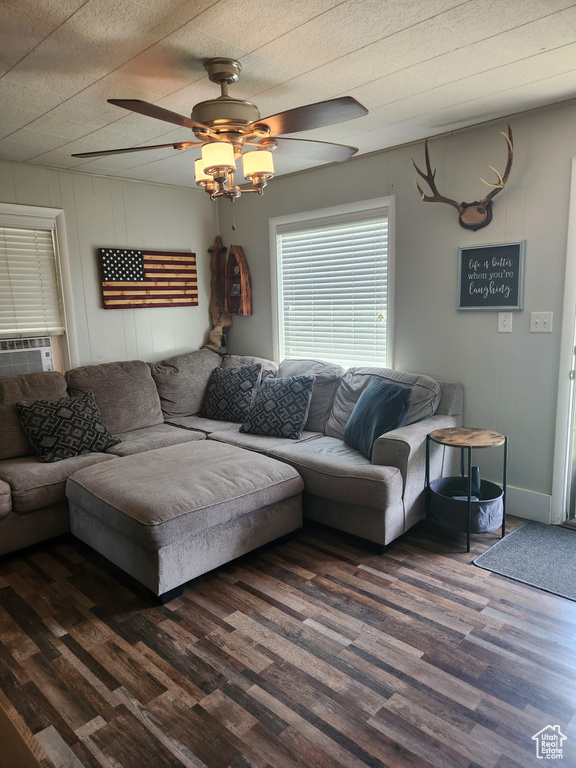 Living area featuring dark wood-style flooring, ceiling fan, and cooling unit