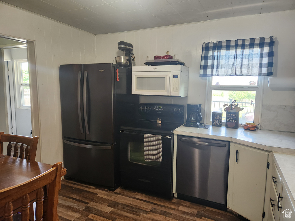 Kitchen with black appliances, dark wood finished floors, light countertops, and white cabinets