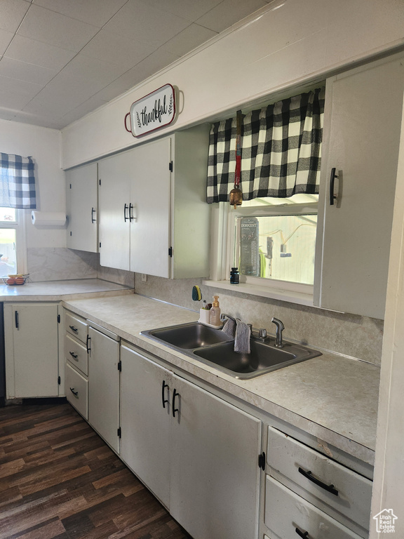 Kitchen featuring a sink, dark wood finished floors, light countertops, and white cabinets