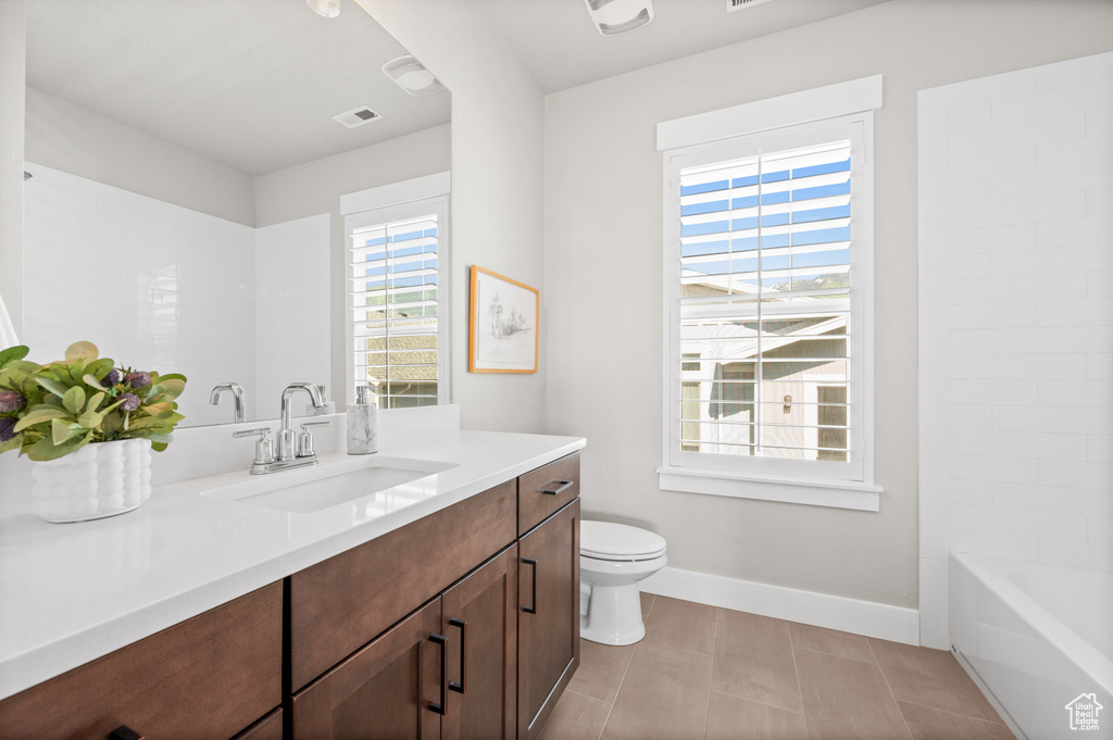 Bathroom featuring vanity, healthy amount of natural light, toilet, and baseboards