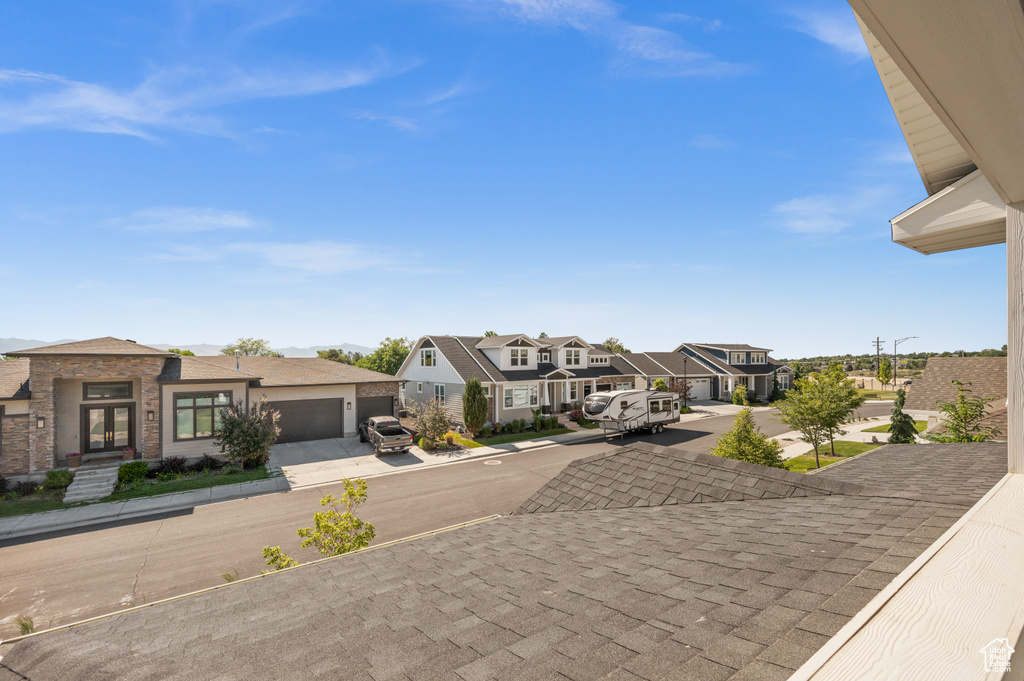 View of front facade with a residential view, concrete driveway, french doors, and an attached garage