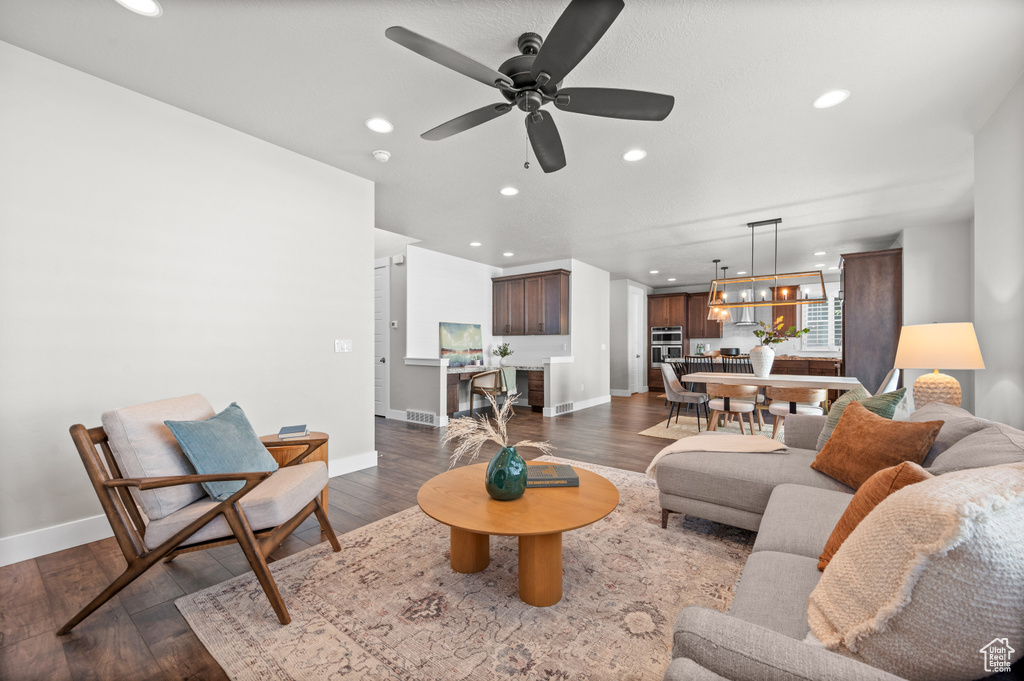 Living area with recessed lighting, baseboards, dark wood-type flooring, and ceiling fan