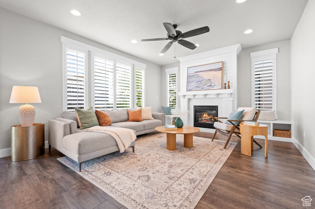 Living area with a fireplace, recessed lighting, dark wood-style floors, a ceiling fan, and baseboards