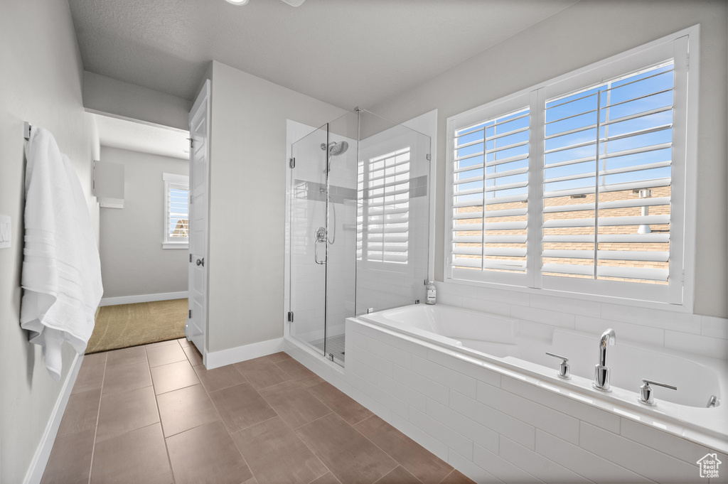 Full bathroom with a garden tub, a stall shower, and baseboards