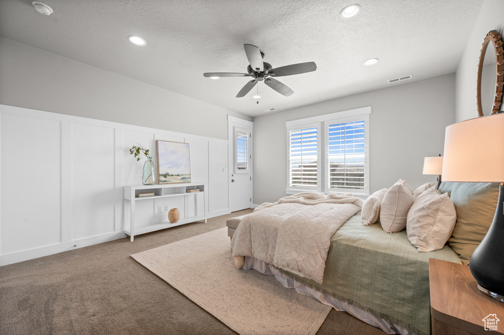 Bedroom featuring a textured ceiling, carpet, a ceiling fan, recessed lighting, and a decorative wall