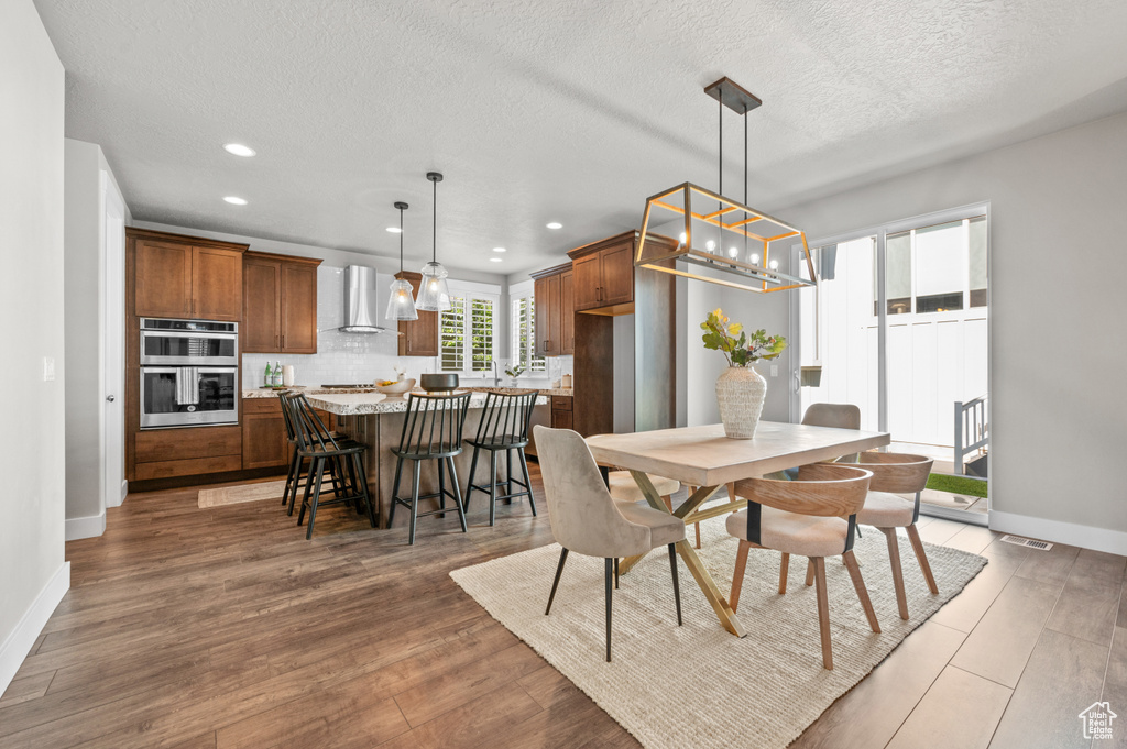 Dining room featuring recessed lighting, baseboards, light wood finished floors, and a textured ceiling