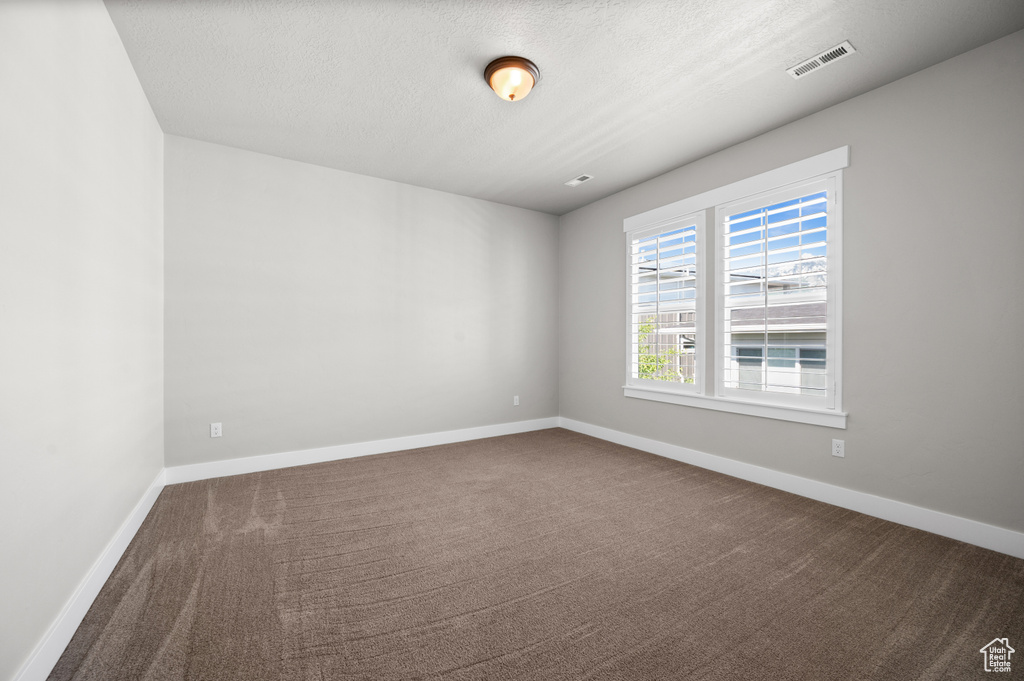 Unfurnished room featuring carpet, a textured ceiling, and baseboards