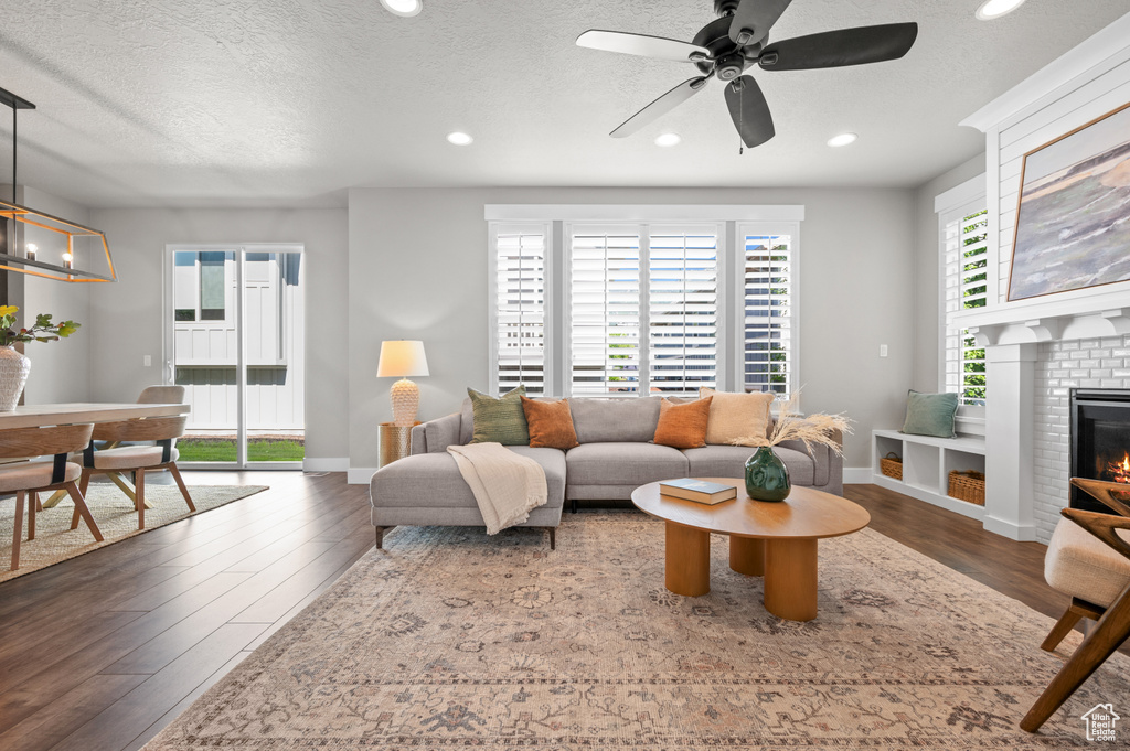 Living room featuring wood finished floors, a ceiling fan, baseboards, recessed lighting, and a fireplace