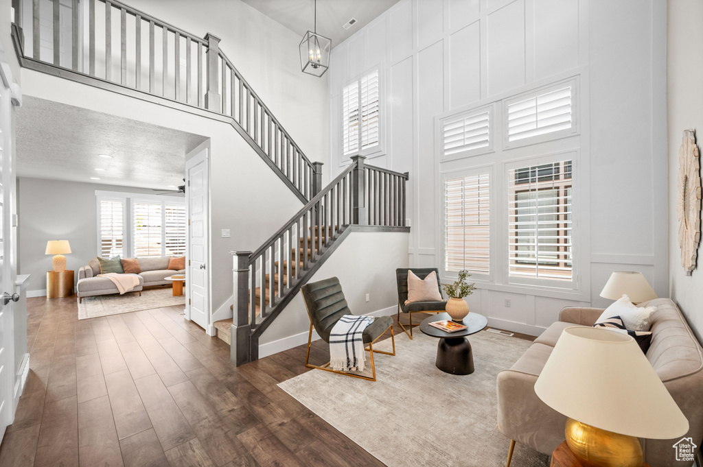 Living room with stairway, dark wood-style flooring, baseboards, a towering ceiling, and a decorative wall
