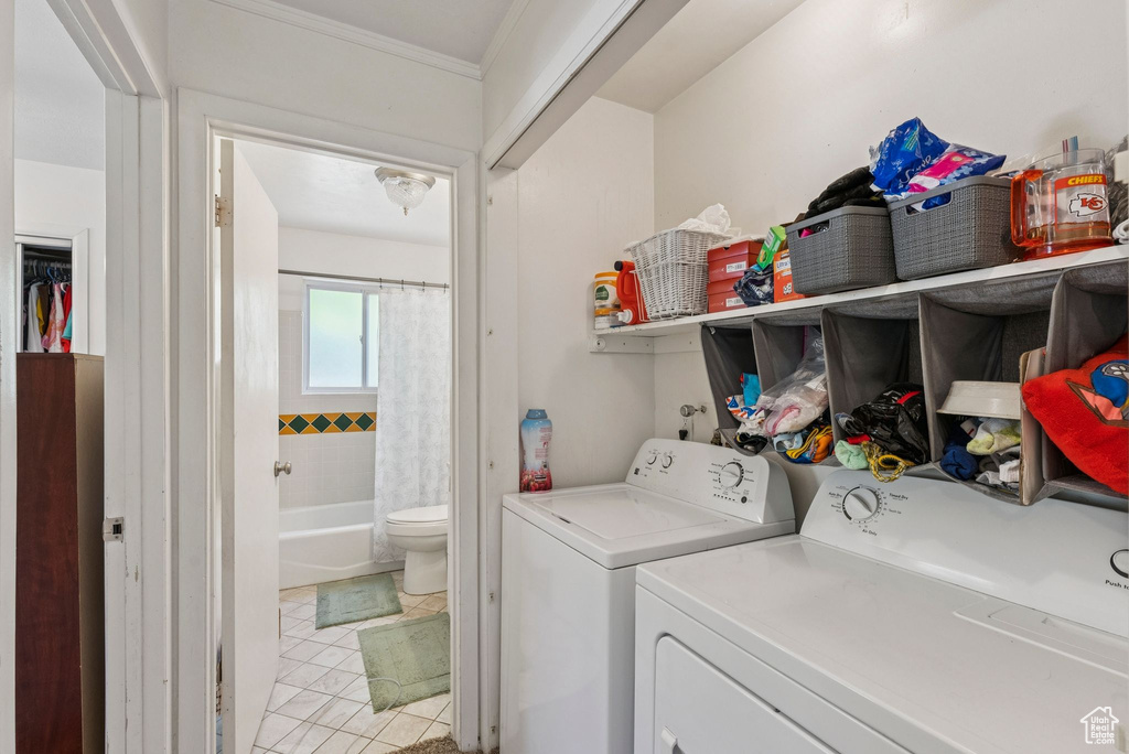 Laundry area with washing machine and clothes dryer, light tile patterned flooring, and ornamental molding
