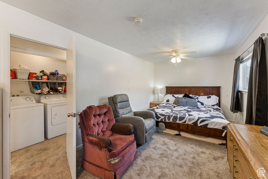Bedroom featuring light carpet, separate washer and dryer, and a ceiling fan