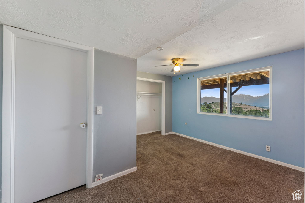 Unfurnished bedroom featuring carpet floors, a textured ceiling, baseboards, and a closet
