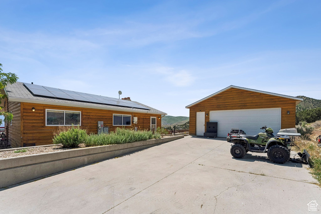 View of front facade featuring solar panels, a detached garage, and an outbuilding