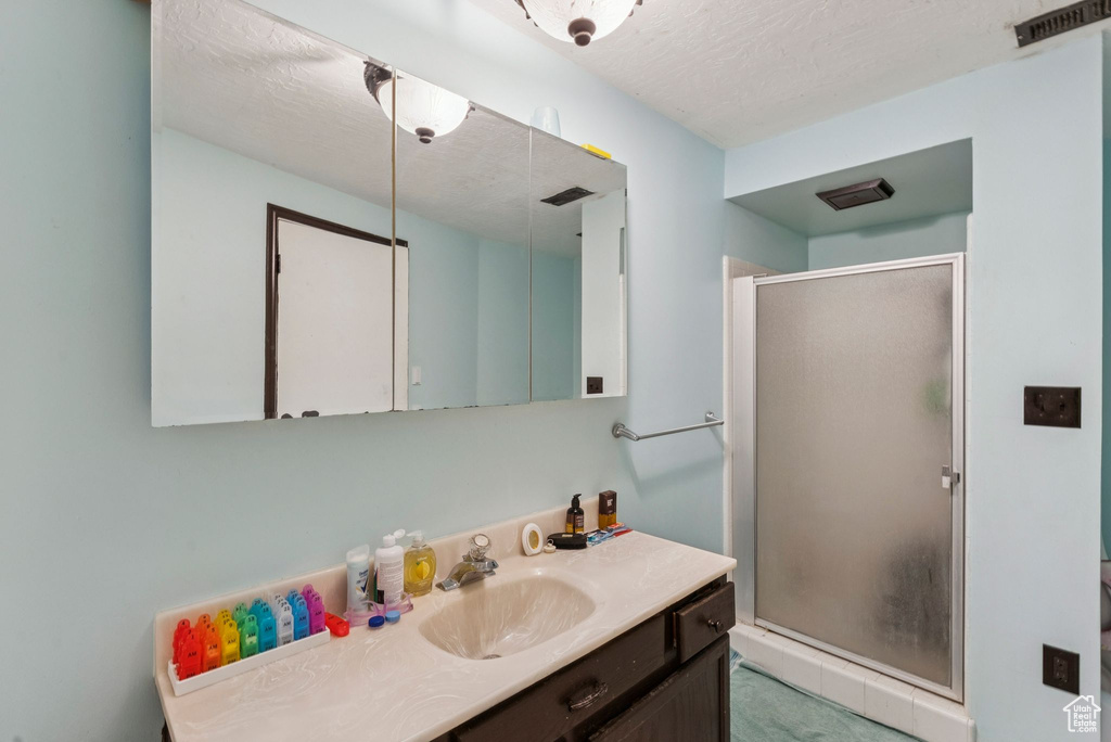 Bathroom with vanity, a stall shower, and a textured ceiling