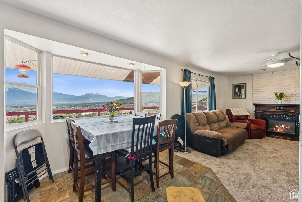 Dining room with a mountain view, a glass covered fireplace, and ceiling fan