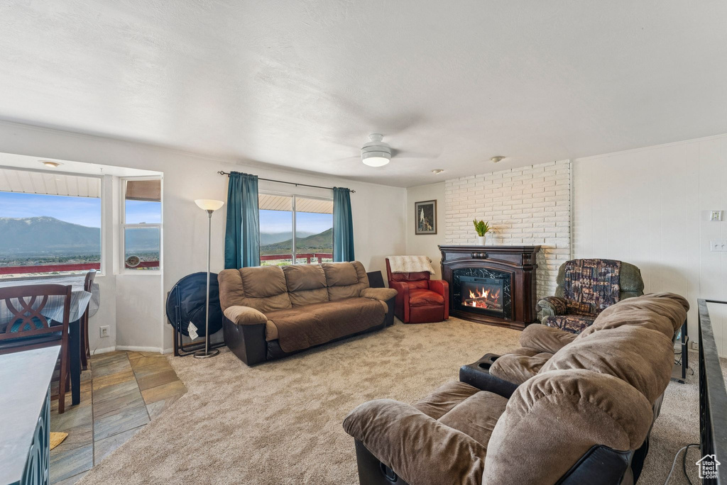 Living area with ceiling fan, a glass covered fireplace, and a mountain view
