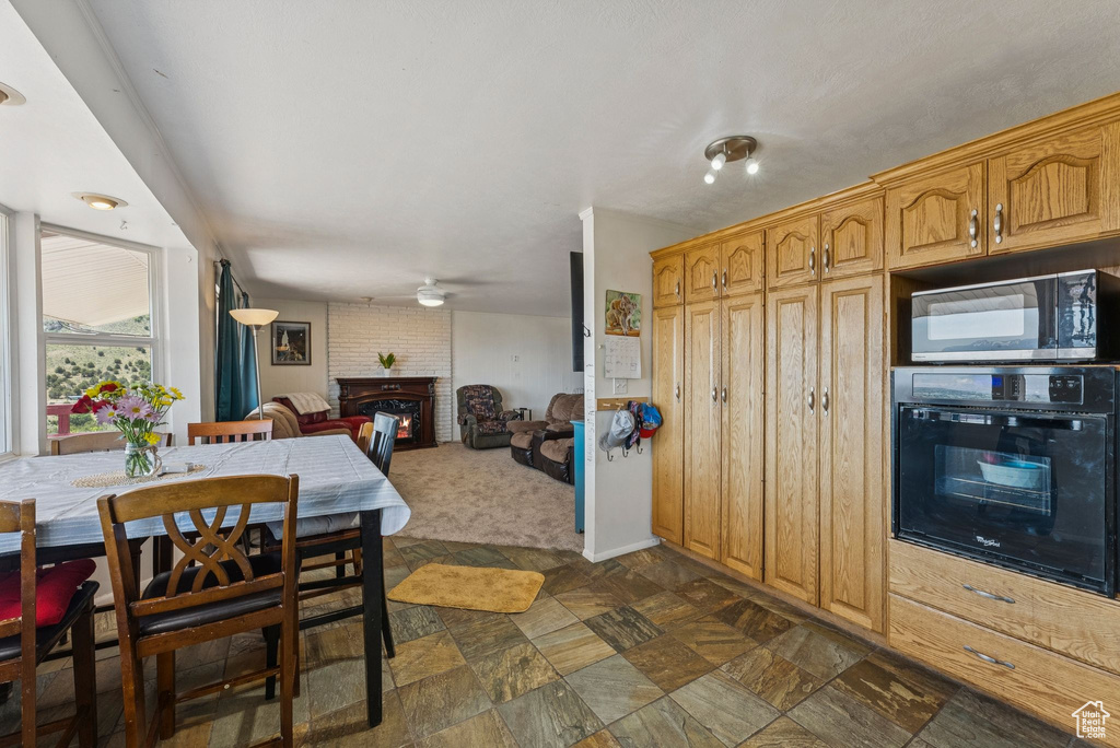 Dining space with a brick fireplace and ceiling fan