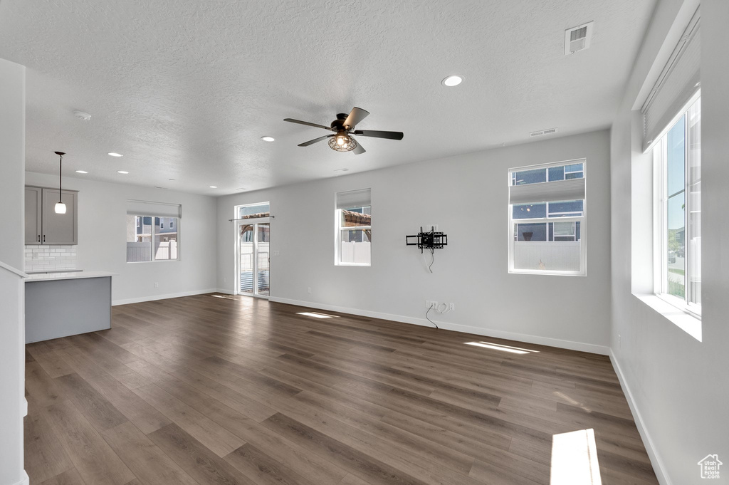 Unfurnished living room featuring baseboards, a textured ceiling, recessed lighting, ceiling fan, and dark wood-type flooring