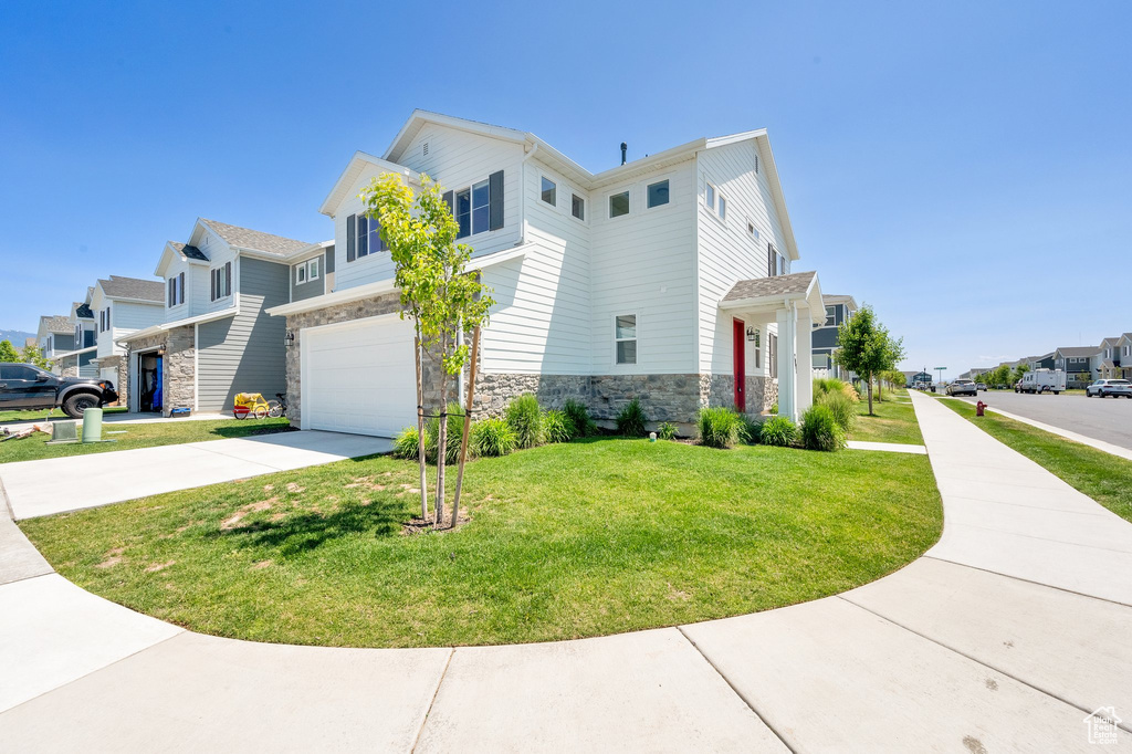 View of property exterior with a residential view, driveway, stone siding, an attached garage, and a lawn