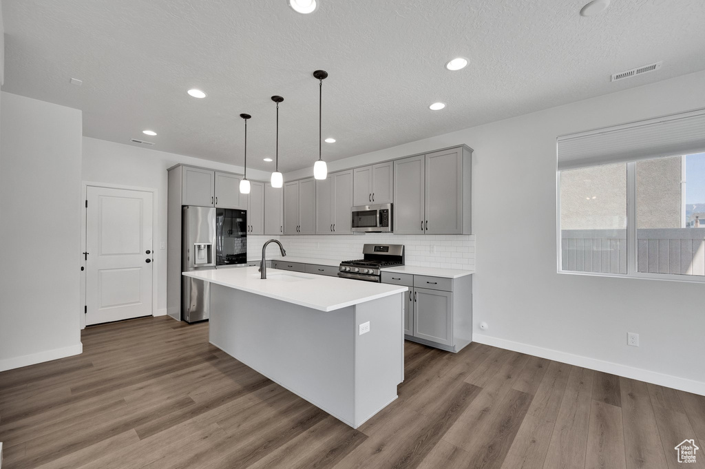 Kitchen featuring stainless steel appliances, gray cabinets, baseboards, a sink, and recessed lighting