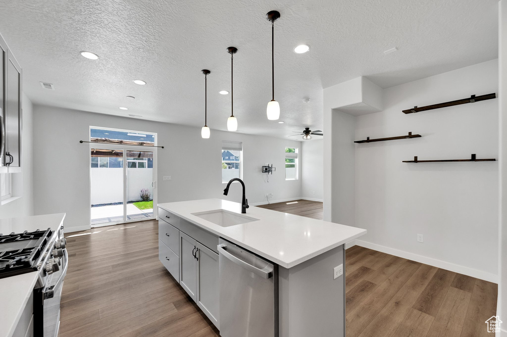 Kitchen featuring a sink, stainless steel appliances, light countertops, wood finished floors, and a textured ceiling