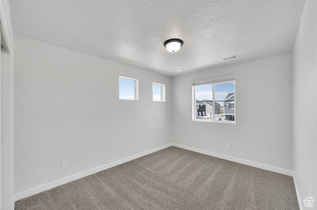 Spare room with a textured ceiling, baseboards, and carpet