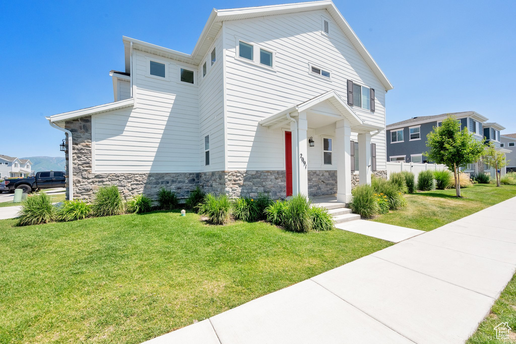 View of front of house featuring stone siding, a front yard, and a residential view