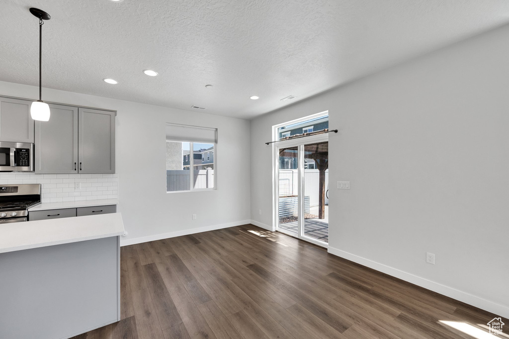 Unfurnished living room featuring baseboards, dark wood finished floors, recessed lighting, and a textured ceiling