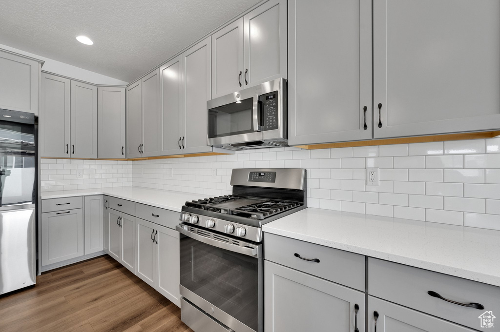 Kitchen featuring appliances with stainless steel finishes, gray cabinetry, light countertops, a textured ceiling, and recessed lighting
