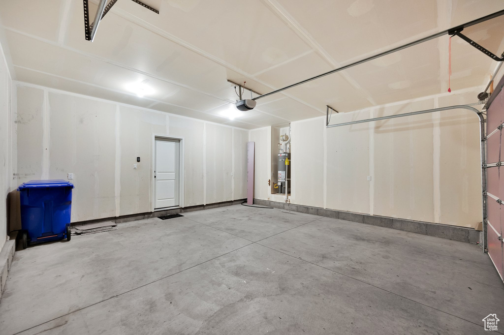 Garage with strapped water heater and a garage door opener