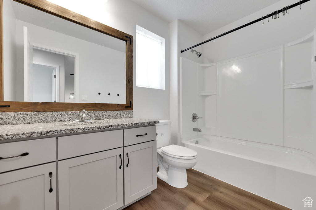 Bathroom with wood finished floors, vanity,  shower combination, and toilet
