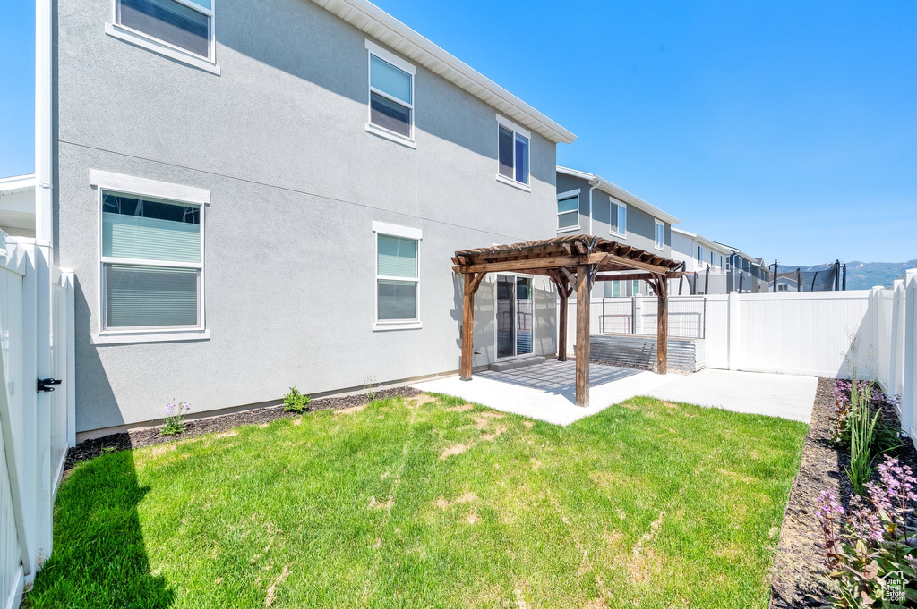 Rear view of property featuring a pergola, a patio, and stucco siding