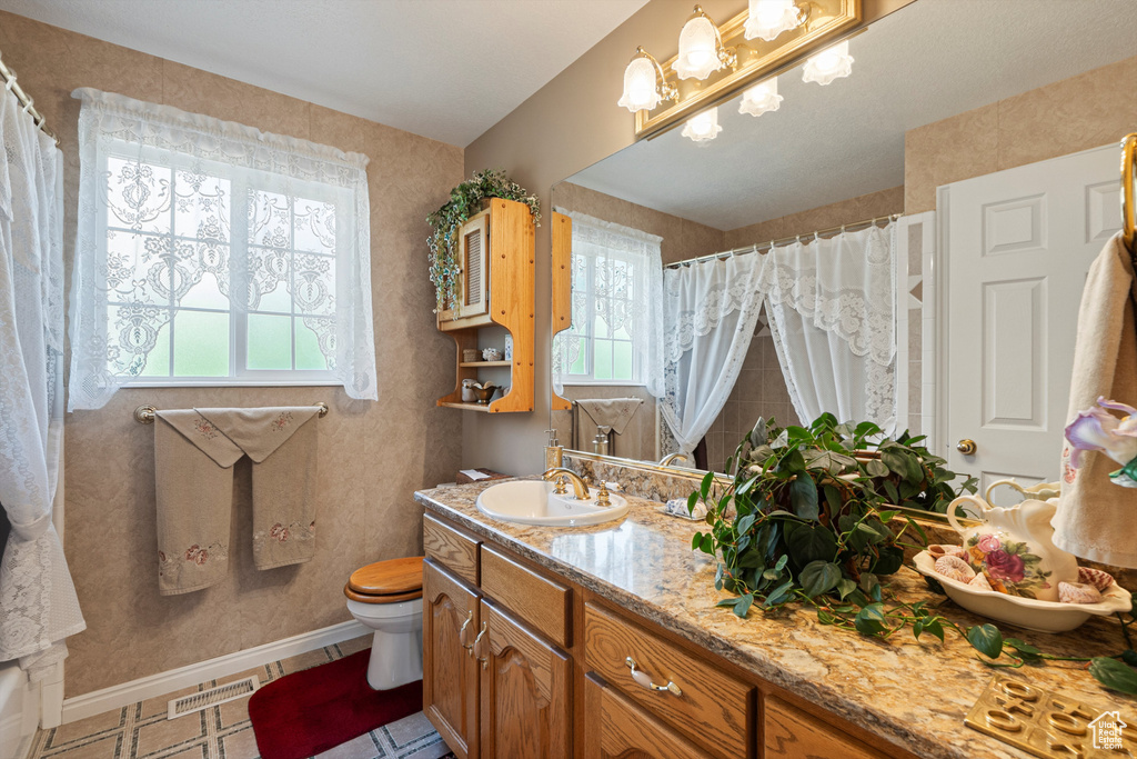 Bathroom with healthy amount of natural light, toilet, vanity, and baseboards