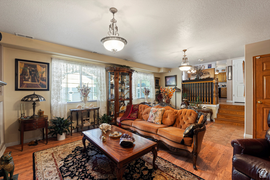 Living area with a textured ceiling, stairway, light wood-type flooring, and baseboards